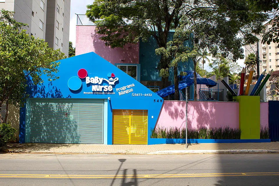 Fachada da Baby Nurse, com o prédio azul e rosa e o portão amarelo