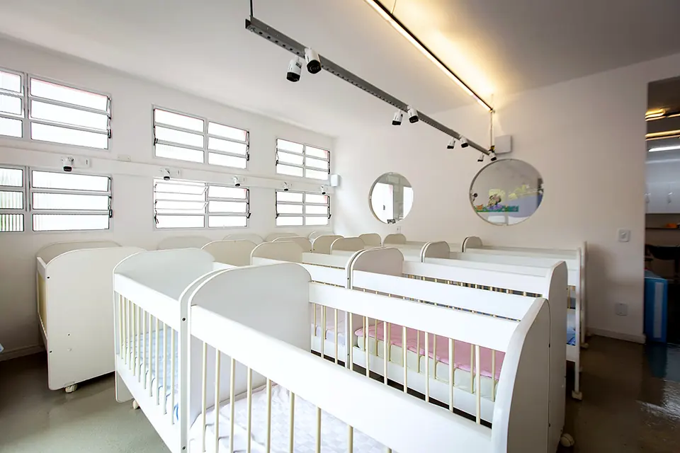 Berçário com berços brancos e iluminação natural