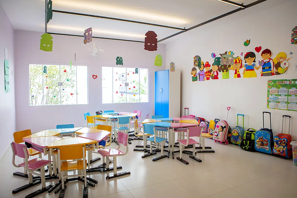 Sala de aula com mesas redondas e cadeiras coloridas